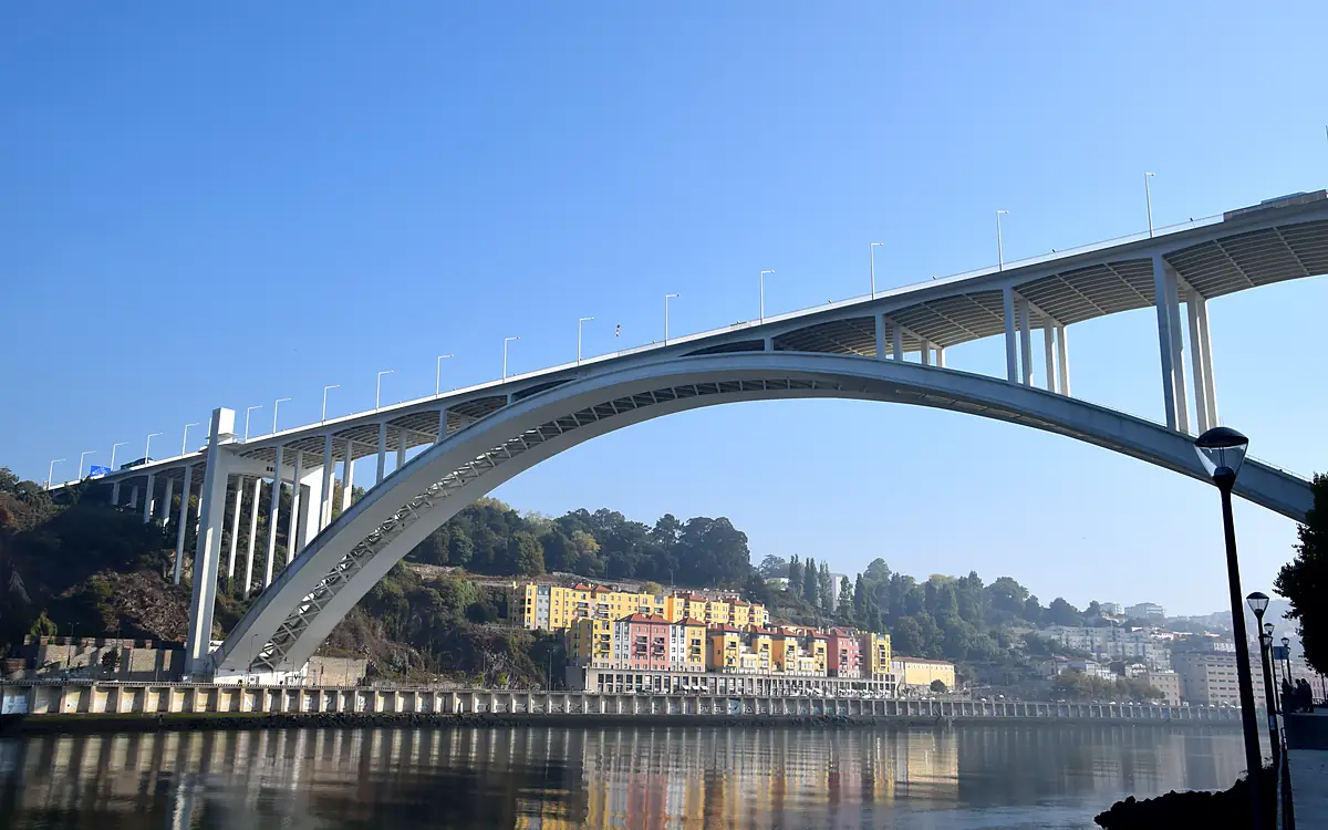 De Ponte da Arrábida in volle breedte vanaf de kade, met de gekleurde huizen van de oever eronder en de weerspiegeling in het water