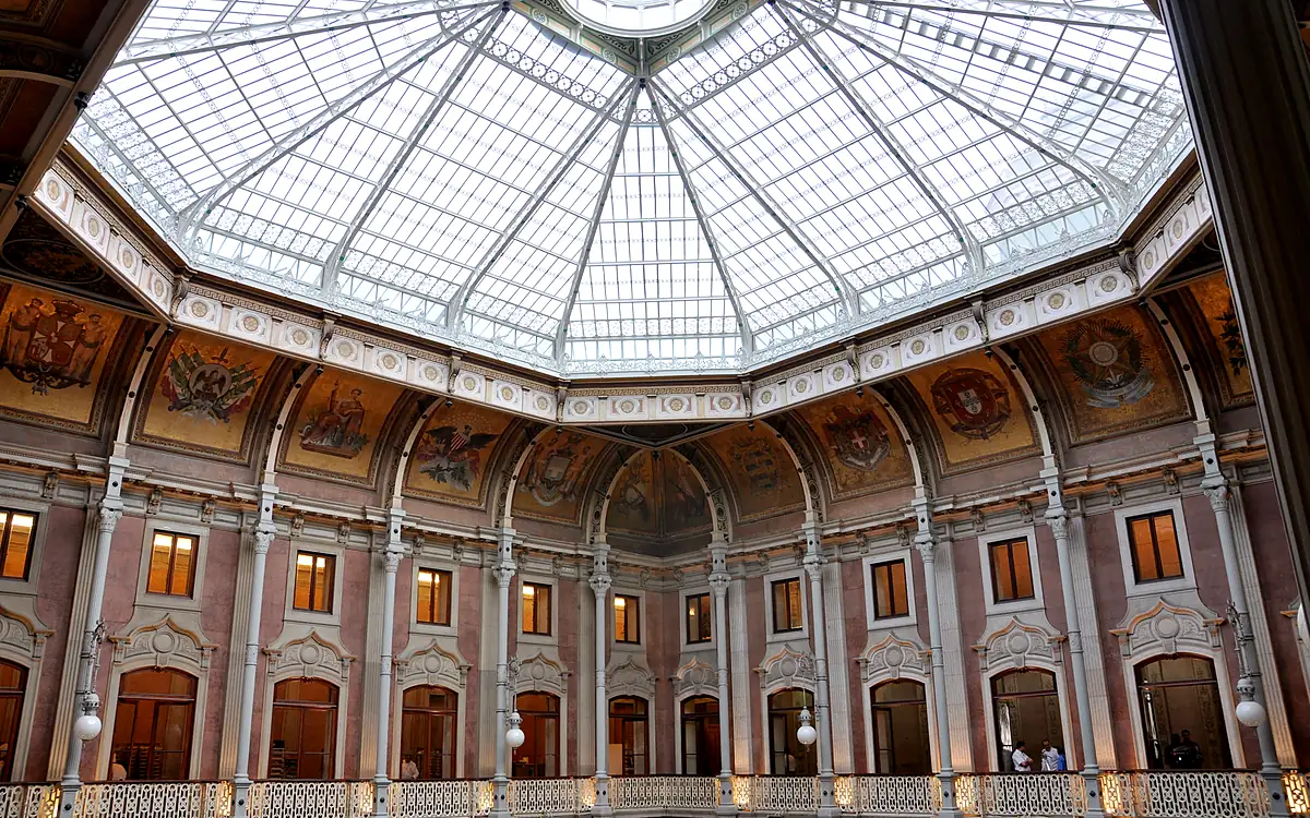 De glazen koepel boven het Pátio das Nações in het Palácio da Bolsa in Porto, met de arcade en de wapenschilden eronder