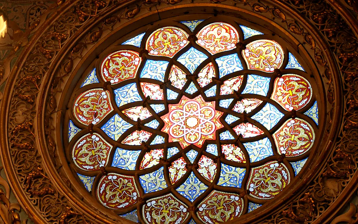 Het glas-in-loodrozet in het plafond van de Salão Árabe in het Palácio da Bolsa, in rood, blauw en goud