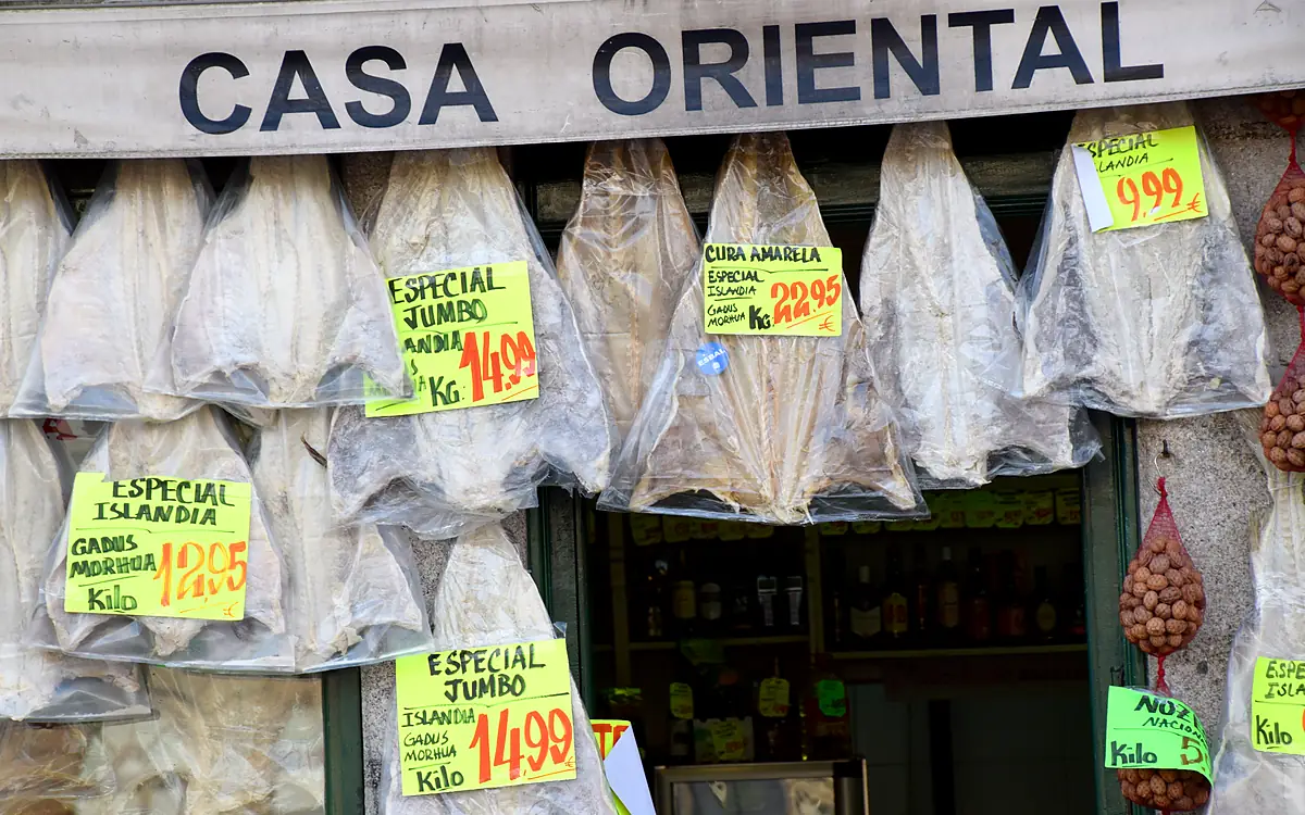 Gedroogde kabeljauw in zakken aan de gevel van Casa Oriental, met gele prijskaartjes