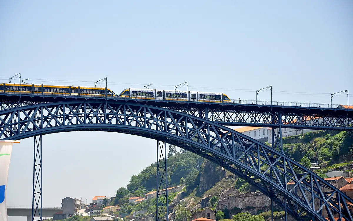 Een metrostel rijdt over het bovendek van de Ponte Dom Luís I in Porto, boven de stalen boog die de Douro overspant
