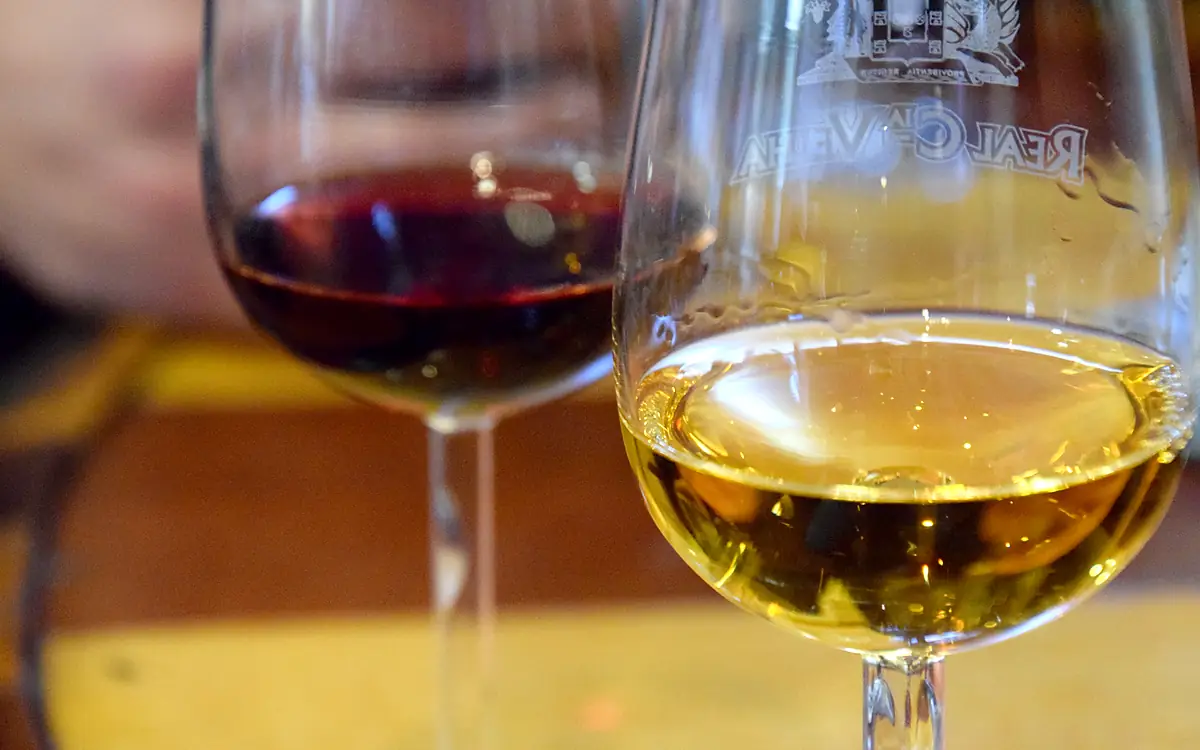 Twee glazen port naast elkaar op een tafel, links een rode en rechts een witte