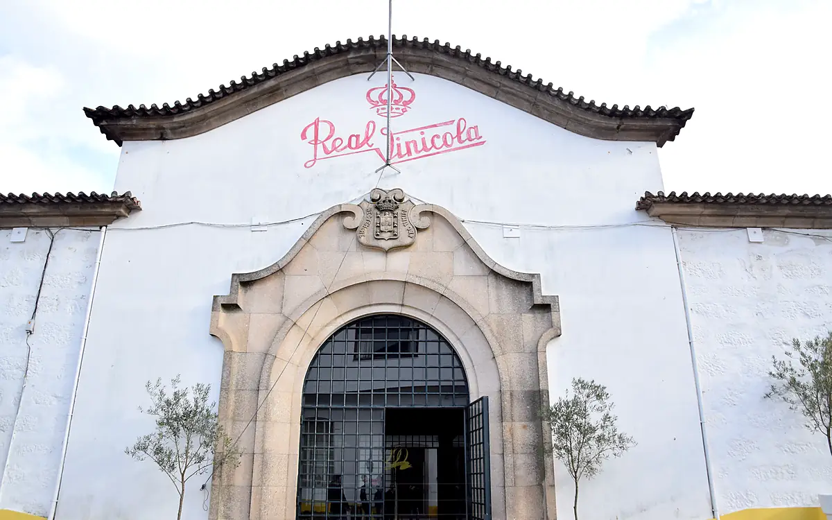 Witte gevel met de naam Real Vinícola in roze letters