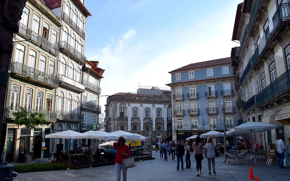 De Praça da Ribeira met terrassen onder witte parasols en wandelaars tussen de omringende gevels