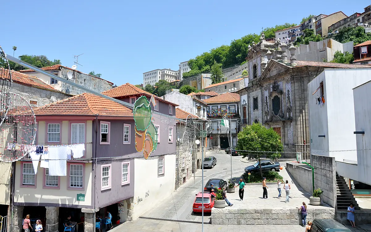 Een straat in de Ribeira met wasgoed aan de lijn en een barokke kerkgevel, met de begroeide helling erachter