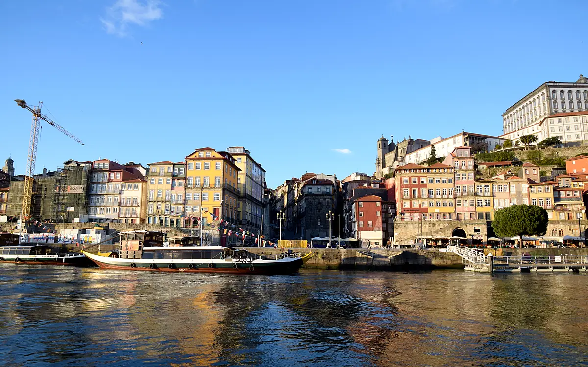 De gekleurde gevelrij van de Ribeira vanaf het water, met rabelo-boten aan de kade en de stad die oploopt tegen de helling