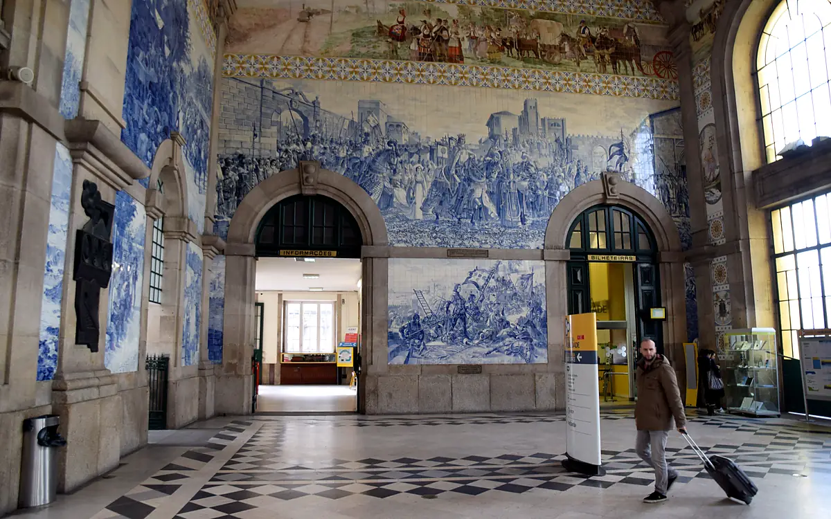 De stationshal van Estação de São Bento met blauw-witte azulejopanelen over de hele wand en een zwart-witte schaakbordvloer