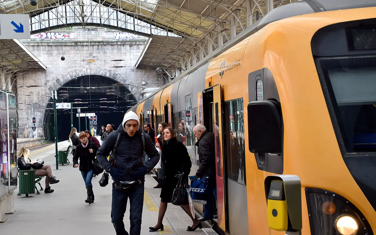 Een geel treinstel aan het perron van station São Bento onder de ijzeren overkapping, met reizigers die uitstappen