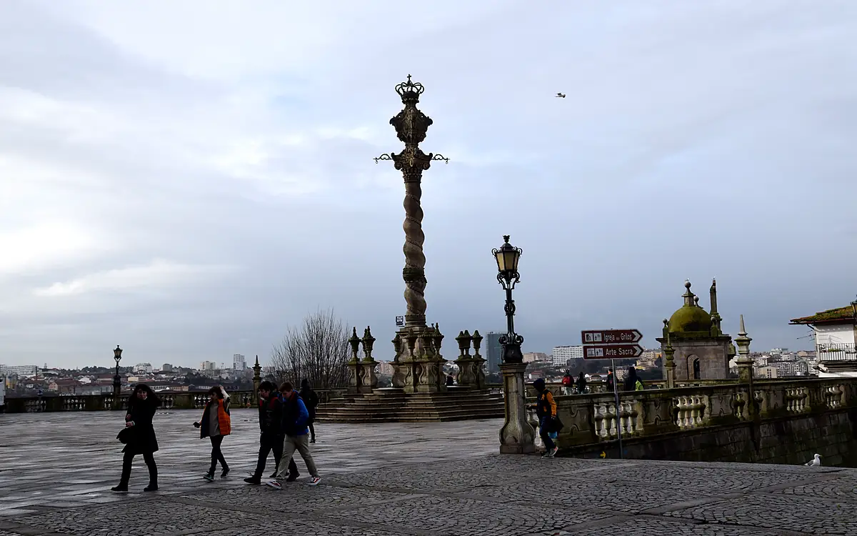De gedraaide schandpaalzuil op het Terreiro da Sé in Porto, met wandelaars op het plein en de stad daarachter