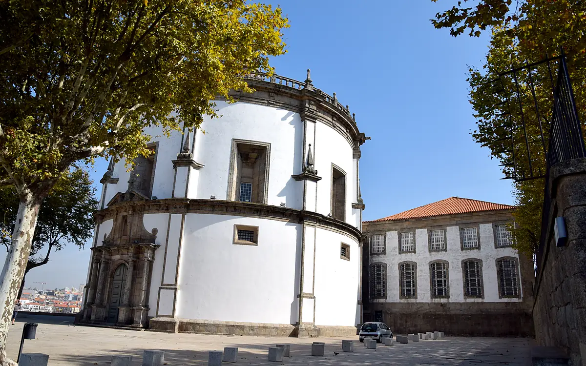De witte ronde koepel van de kerk van Serra do Pilar tussen de bomen, met de kloostergebouwen ernaast